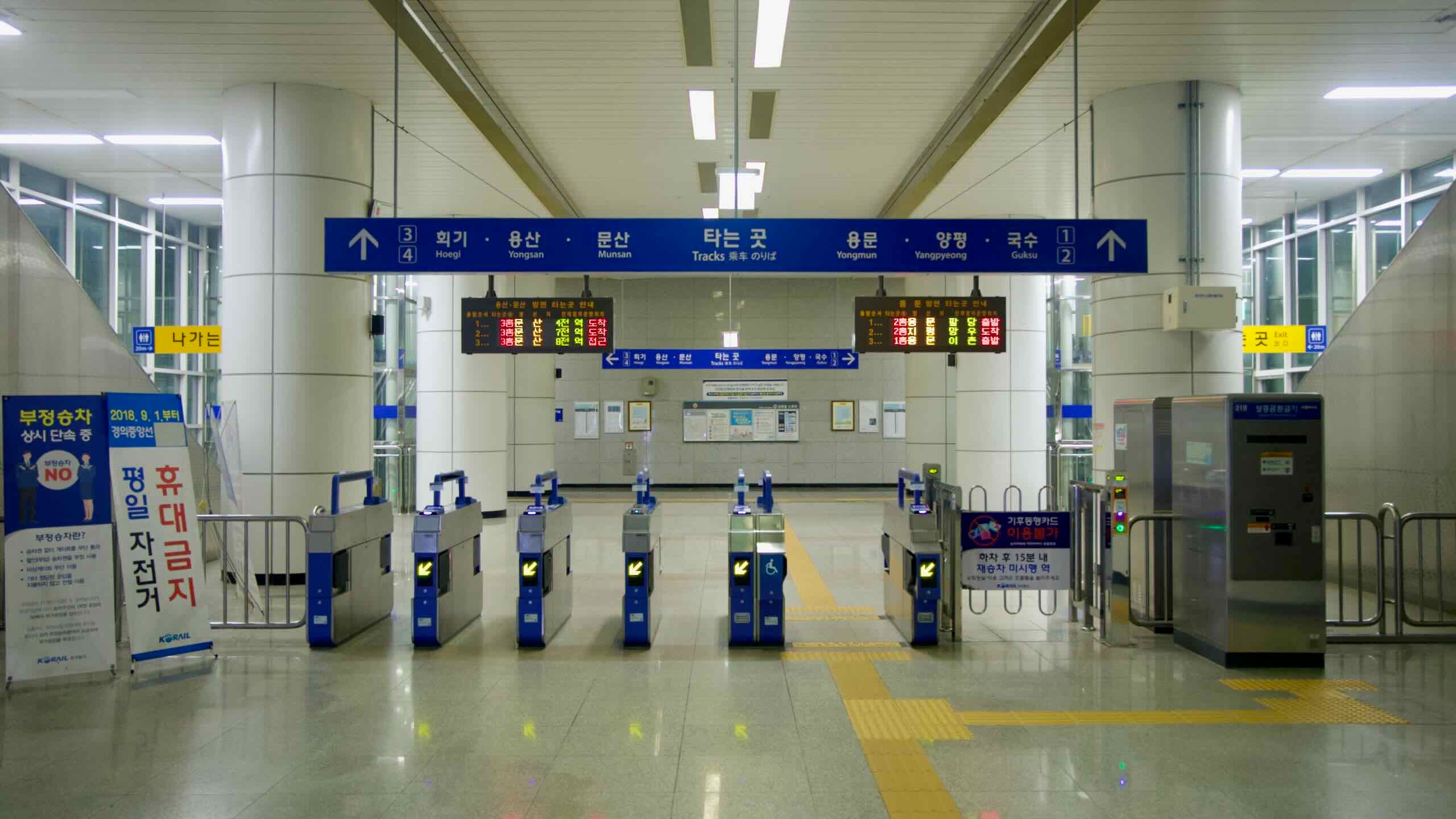 Automated ticket gates and overhead signs lead into the concourse at Ungilsan Station in Namyangju.