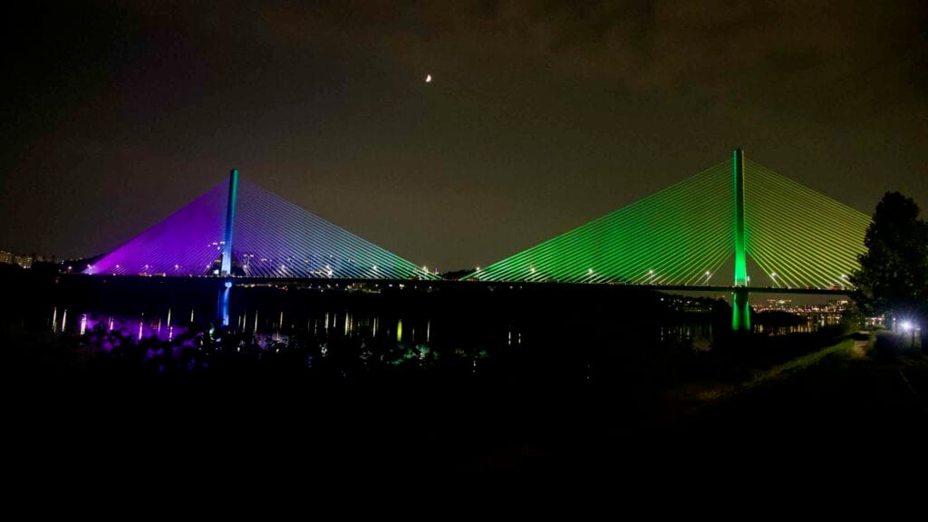 Guri-Amsa Bridge glows green and purple over the Han River at night.