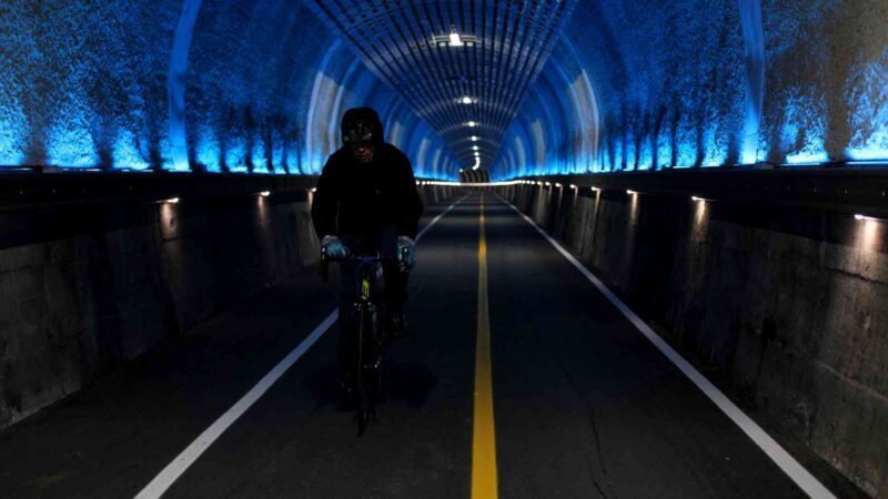 A picture of a cyclists riding through the decommissioned train tunnels of the Namhangang Bicycle Path.