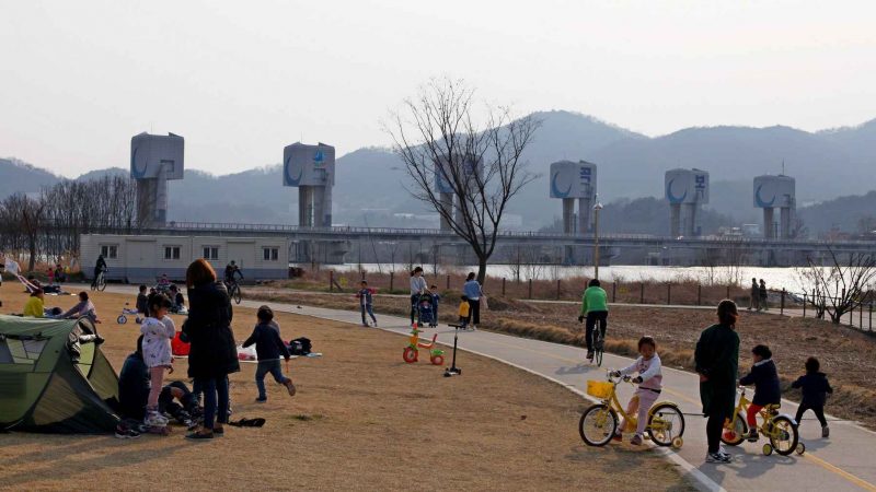 Pedestrians and kids riding bikes enjoy the park next to Chilgok Weir (칠곡보) in Chilgok County, South Korea.