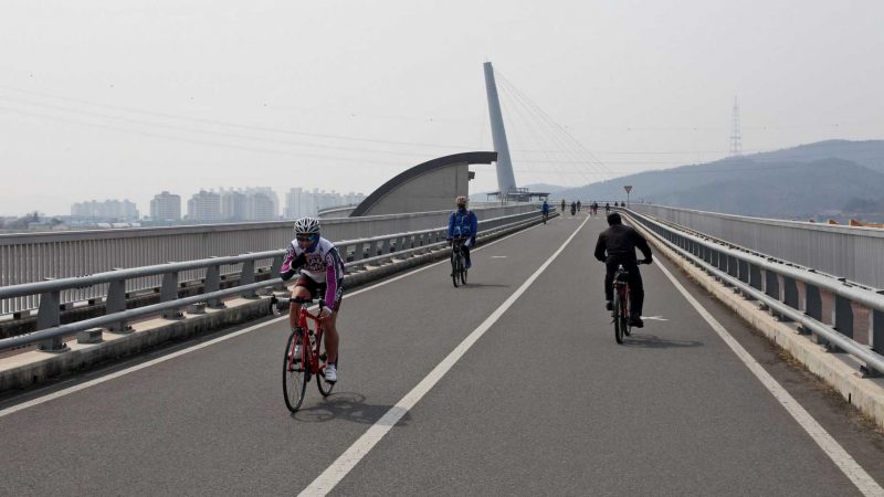 Bike riders cross Gangjeong Goryeong Weir (강정고령보) on the edge of Daegu in South Korea.