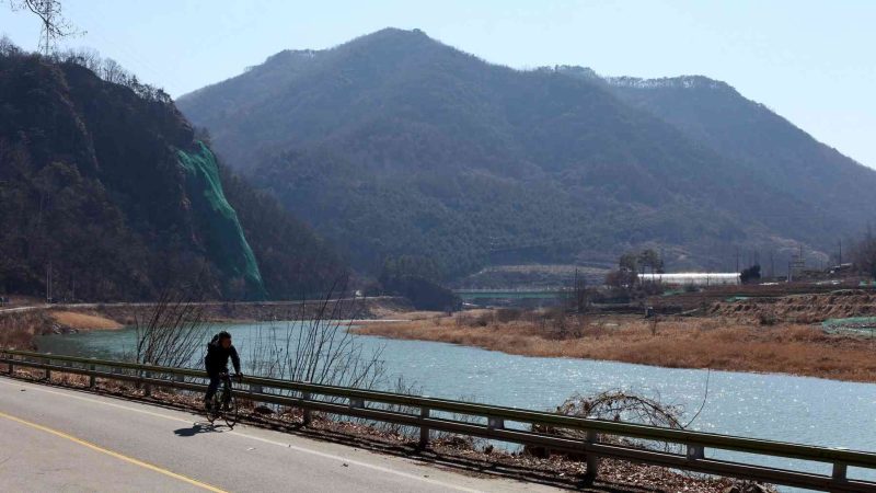 A picture of a cyclists on the roads south of Chungju. Behind the Sobaek Mountain Range rises and the Dal Stream flows.