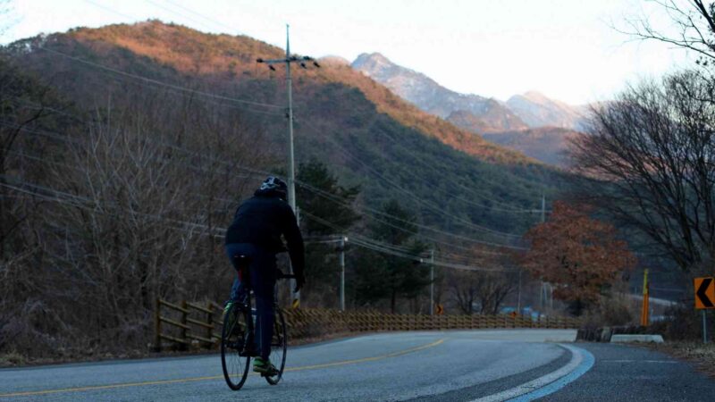 A rider descends an empty country road from the top of Sojo Pass along the Saejae Bike Path in Goesan County, South Korea.